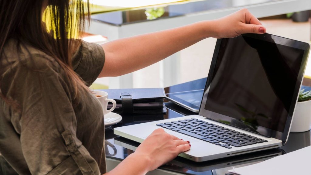 Una mujer usa una computadora portátil con la pantalla en blanco, concentrada en su trabajo.