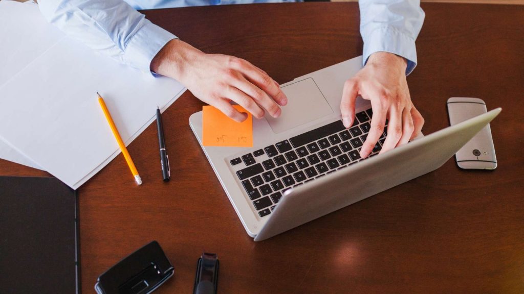 Persona tecleando en una computadora portátil en un entorno de trabajo.
