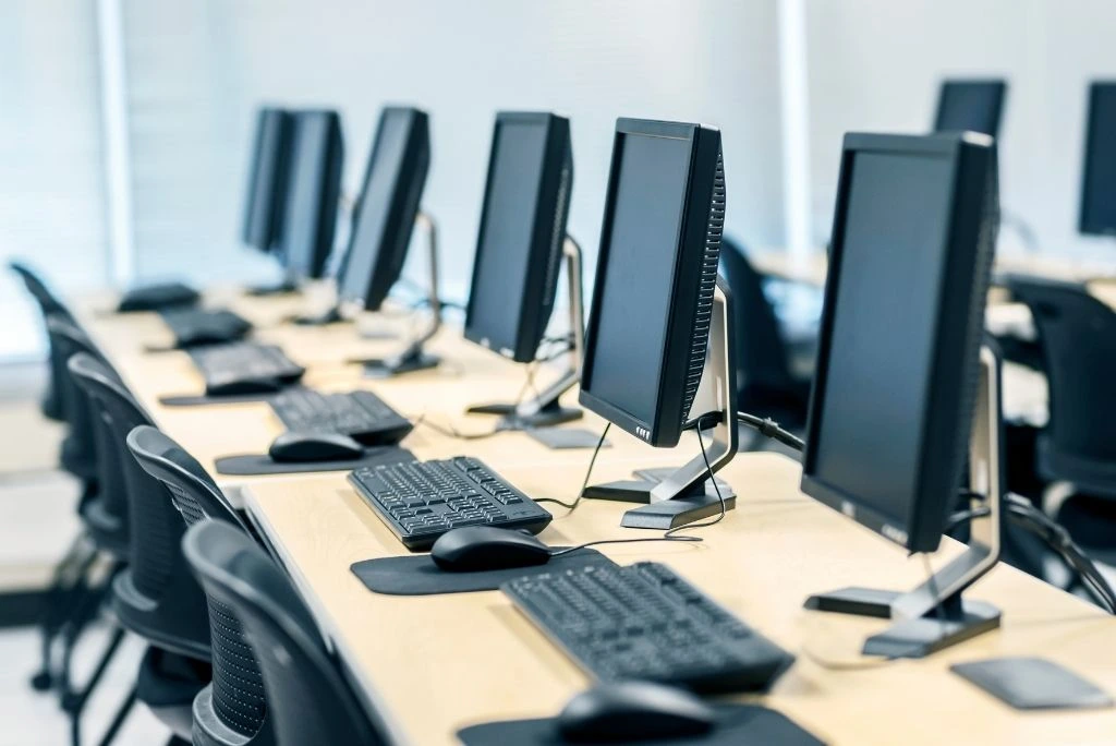 Fila de computadores de escritorio con teclado y mouse en sala corporativa lista para alquiler empresarial en Colombia