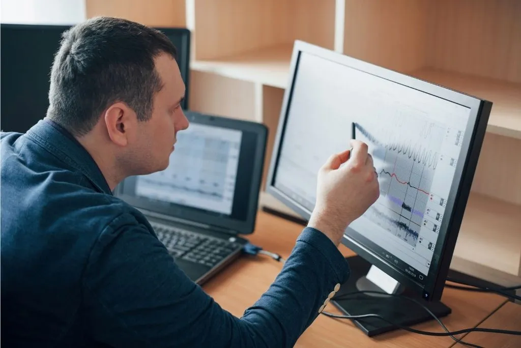Gerente de TI analizando KPIs de eficiencia del parque informático en doble monitor para optimizar equipos empresariales con APG