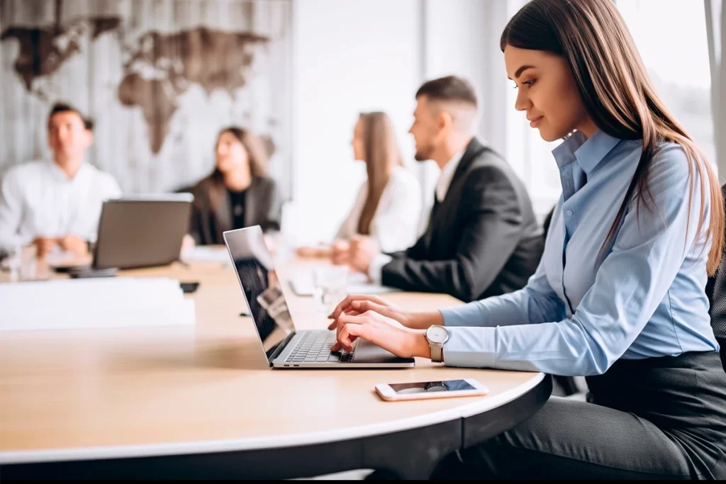 Profesional de firma de servicios trabajando en laptop rentada en sala de reuniones corporativa con equipo de APG Tecnología