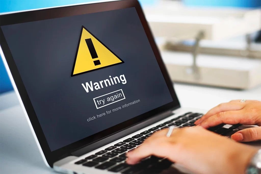 Pantalla de laptop con alerta de advertencia por riesgo de ciberseguridad empresarial.