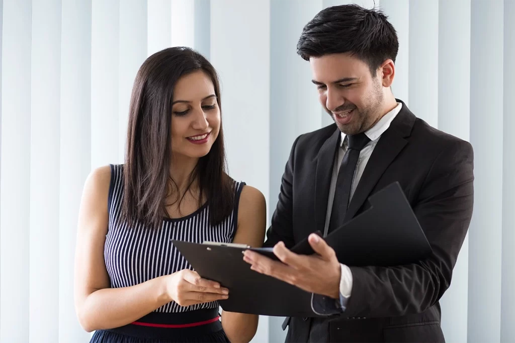 Dos integrantes de fuerza de ventas revisando información en tablet y carpeta.