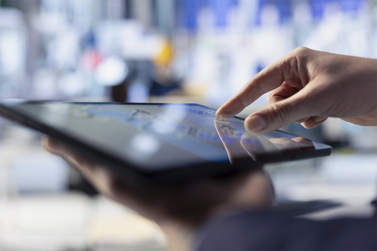 Mano operando tablet para gestión de inventario tecnológico empresarial.