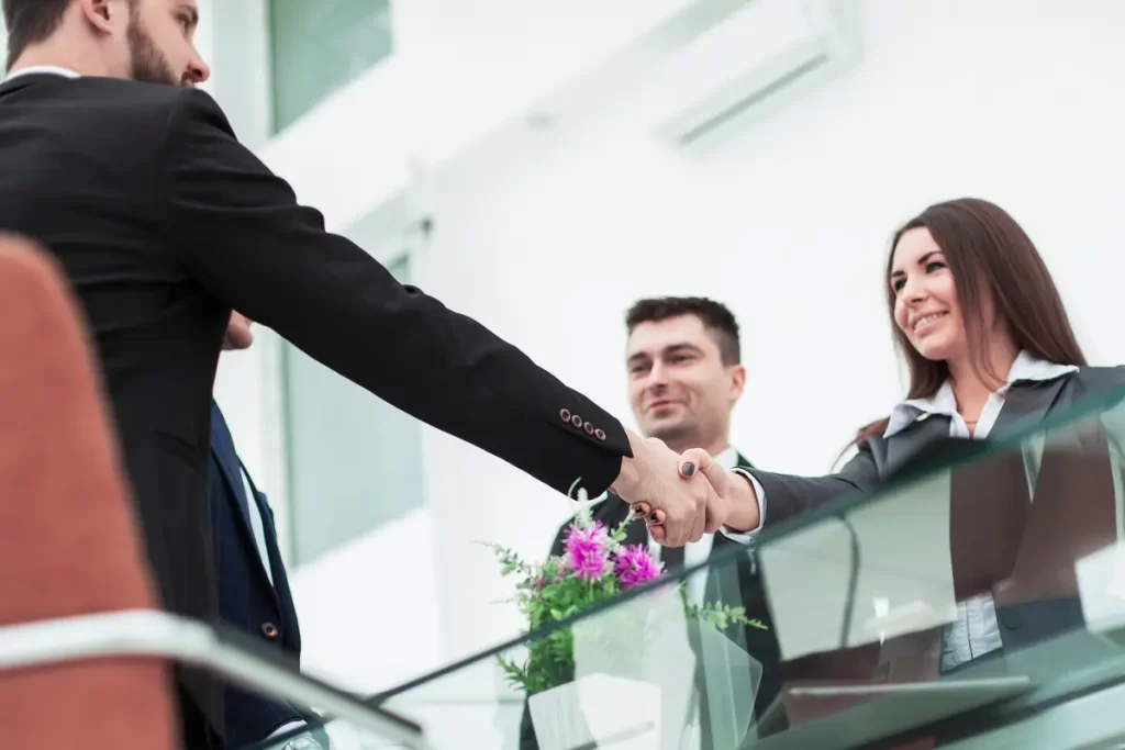 Ejecutivos dándose la mano tras acordar cómo cotizar el alquiler de equipos y el brief de contrato.