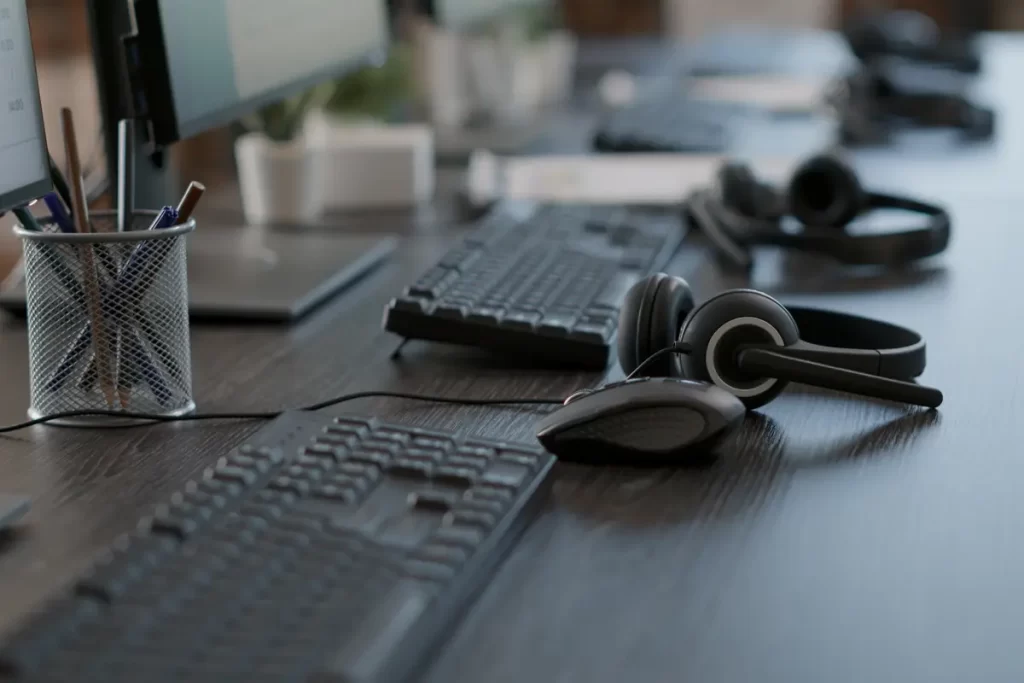 Auriculares para call center con micrófono y ratón sobre un escritorio de oficina moderno.